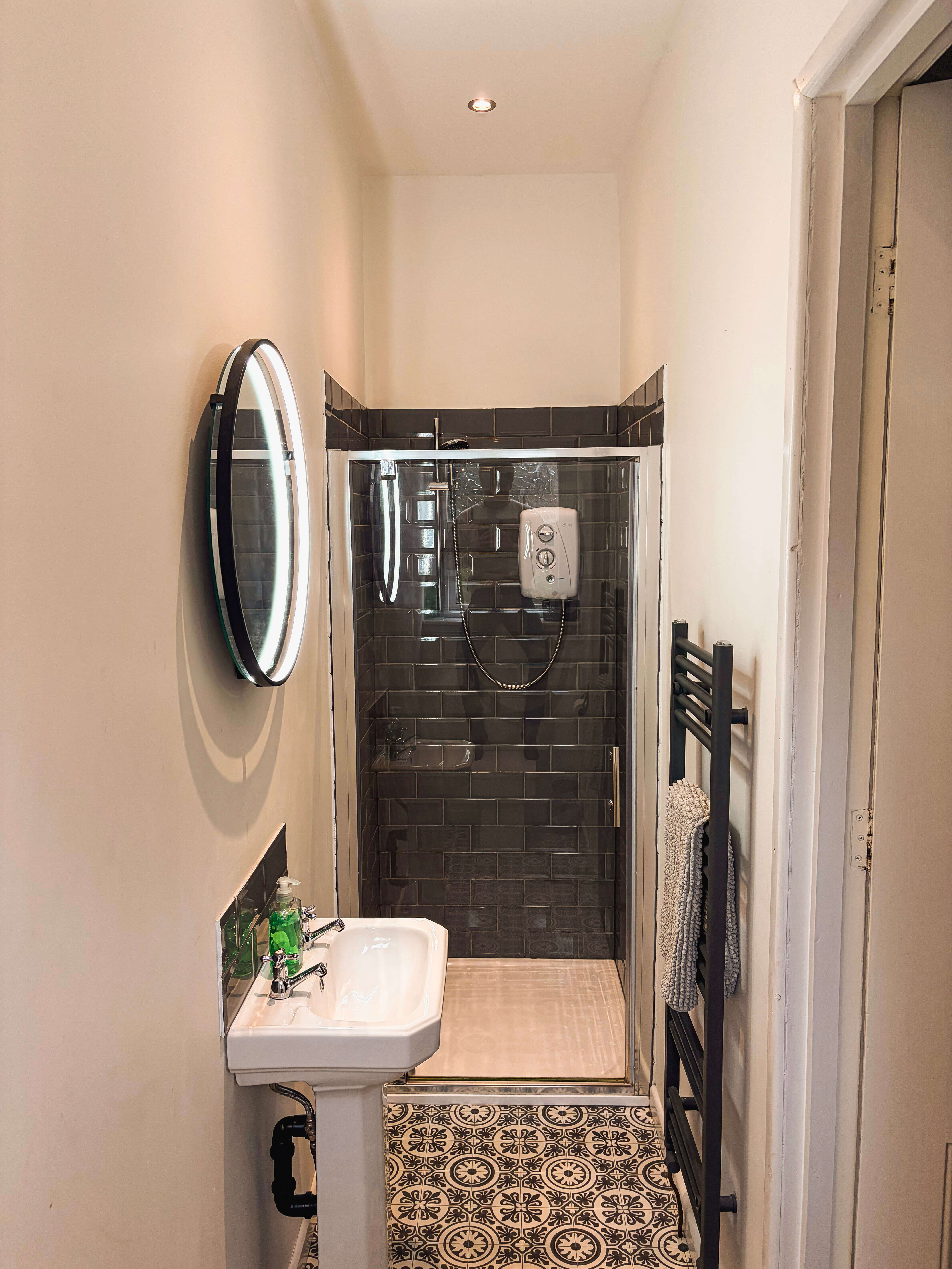 Shared bathroom at Compton Guest House in Buxton with shower, basin and patterned floor